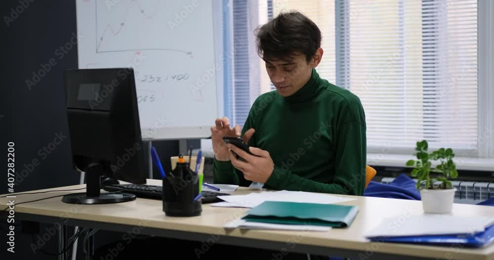 Smiling happy young caucasian man use phone at office Smiling happy young caucasian man use phone at office