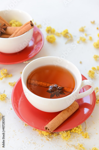 Tasty herbal tea with cinnamon and anise in cups on light background