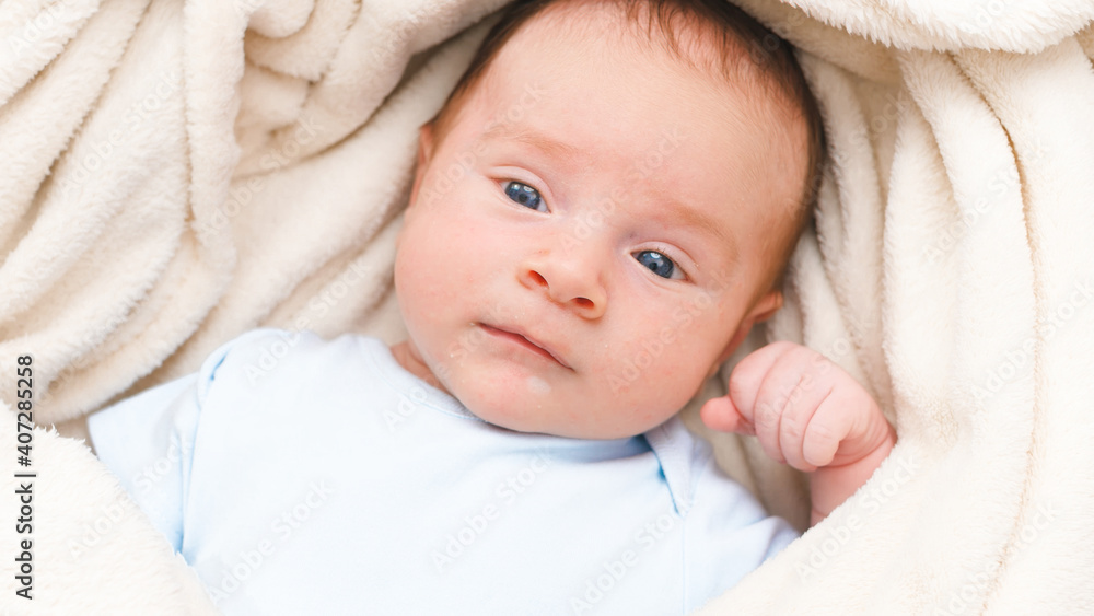 Top view portrait of 1 months old little baby with blue eyes lying on white soft blanket on bed and looking in camera. Top view portrait of 1 months old little baby with blue eyes lying on white soft blanket on bed and looking in camera.