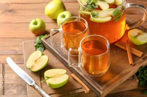 Cups of hot tea with apples and mint on wooden background