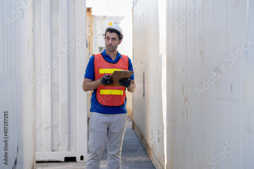 Cargo container worker or foreman hold clipboard and record data about shipping and transfer the product in workplace area. Industrial and factory support system of logistics import export concept.