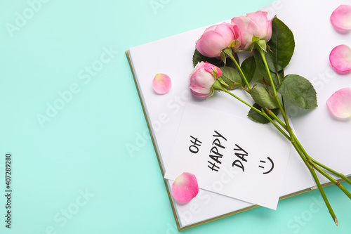 Beautiful pink roses, card and notebook on color background