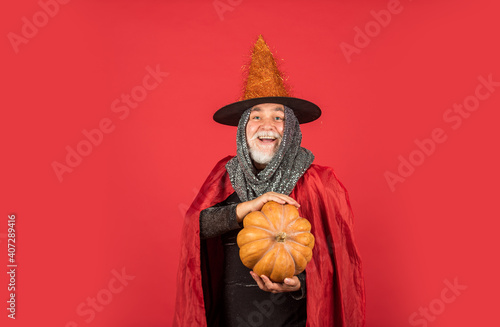 Halloween night party. witch man in hat and cloak. happy halloween. Weird old grandfather with gray beard. Devil man. ready to celebrate halloween. traditional food. Halloween man with pumpkin