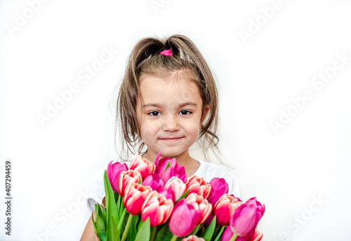 Portrait of a beautiful smiling little girl with spring tulips on a white background. International Women's Day. Girl 5 years old, Caucasian. Isolated.