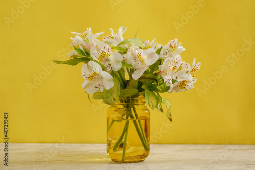Florero amarillo con ramo de flores blancas sobre una mesa de m  rmol y fondo de color amarillo. concepto decoraci  n de interiores