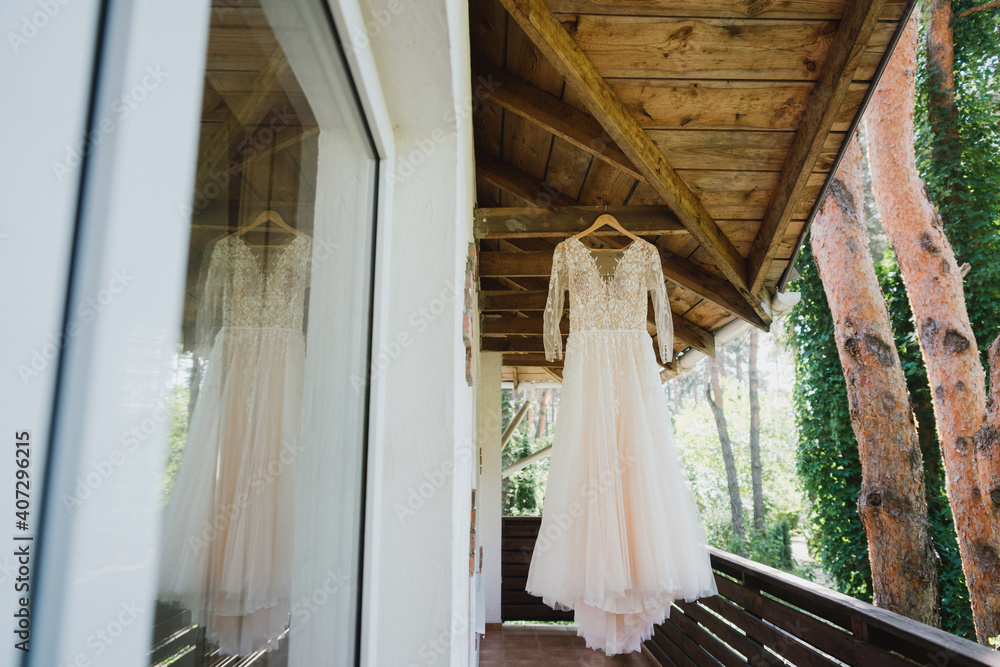 Modern bridal fashion. White and beige wedding dress in casual non-classic style hanging in the hotel room. Modern bridal fashion. White and beige wedding dress in casual non-classic style hanging in the hotel room.
