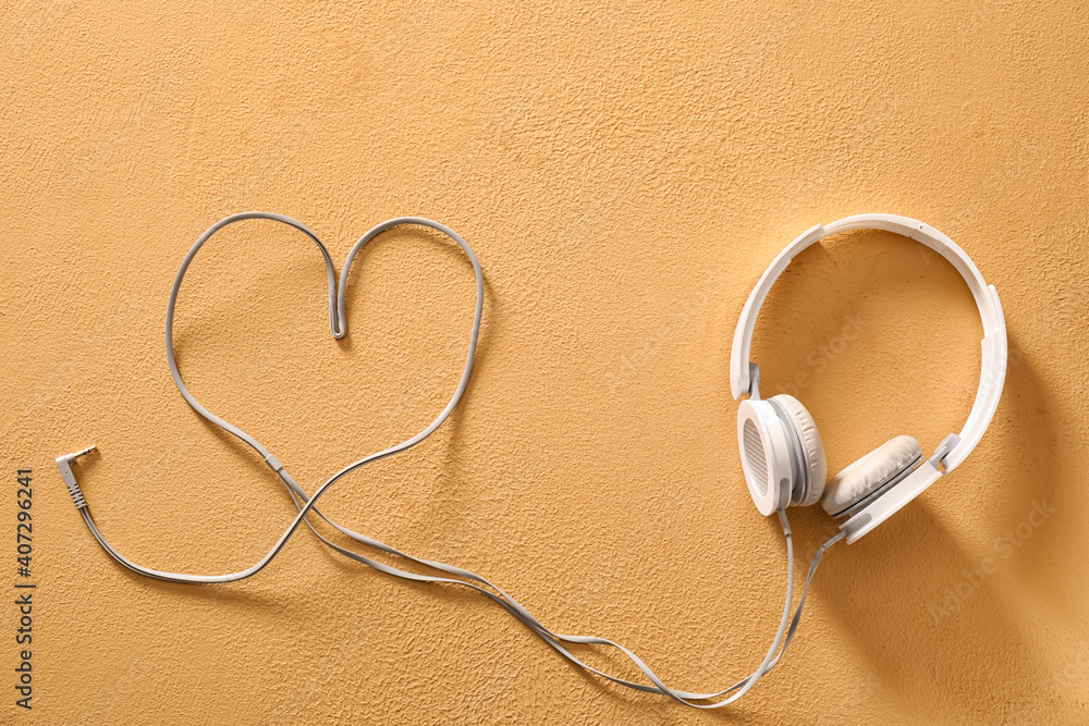 Modern headphones and heart made of wire on color background Modern headphones and heart made of wire on color background