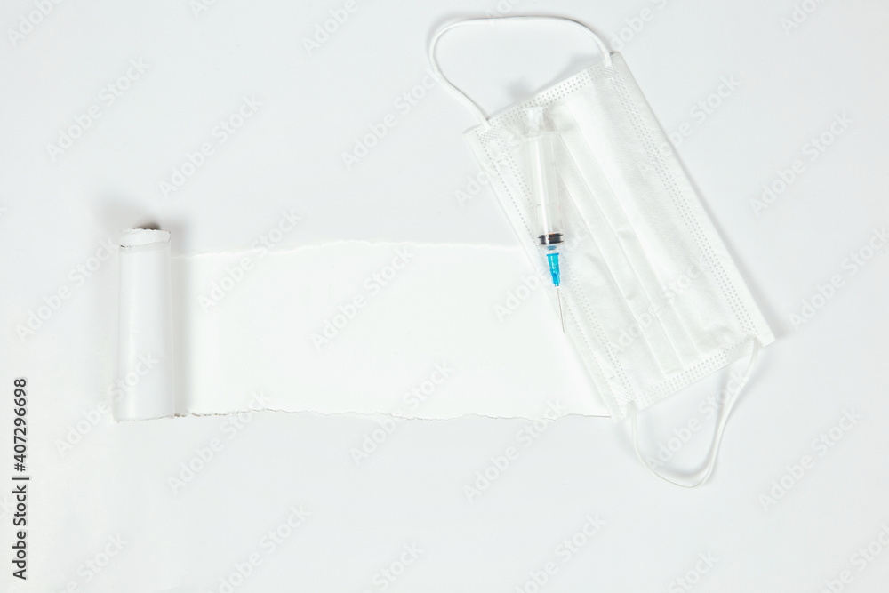 the sheet of torn paper against the white background with syringe and protective white medical mask for virus, Vaccination,health,covid-19 concept. top view, copy space the sheet of torn paper against the white background with syringe and protective white medical mask for virus, Vaccination,health,covid-19 concept. top view, copy space