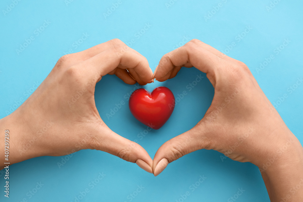 Obraz premium Hands with red heart on color background