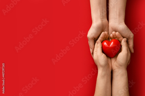 Hands with red heart on color background photo
