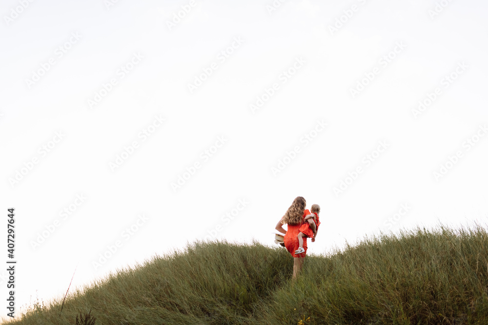 young beautiful mother and little daughter walking on nature on summer day vacation. Mom and girl playing in the field at the sunset time. mothers day. Concept of friendly family young beautiful mother and little daughter walking on nature on summer day vacation. Mom and girl playing in the field at the sunset time. mothers day. Concept of friendly family