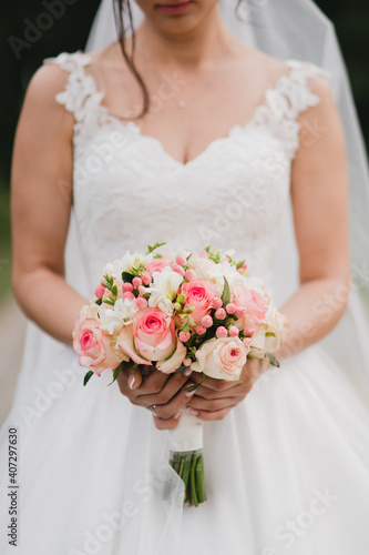 Modern bridal style. Closeup of caucasian bride holding a beautiful bouquet of colorful fresh flowers in her hands.