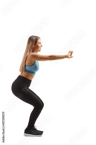 Fototapeta Naklejka Na Ścianę i Meble -  Full length profile shot of a young woman in sportswear exercising squats