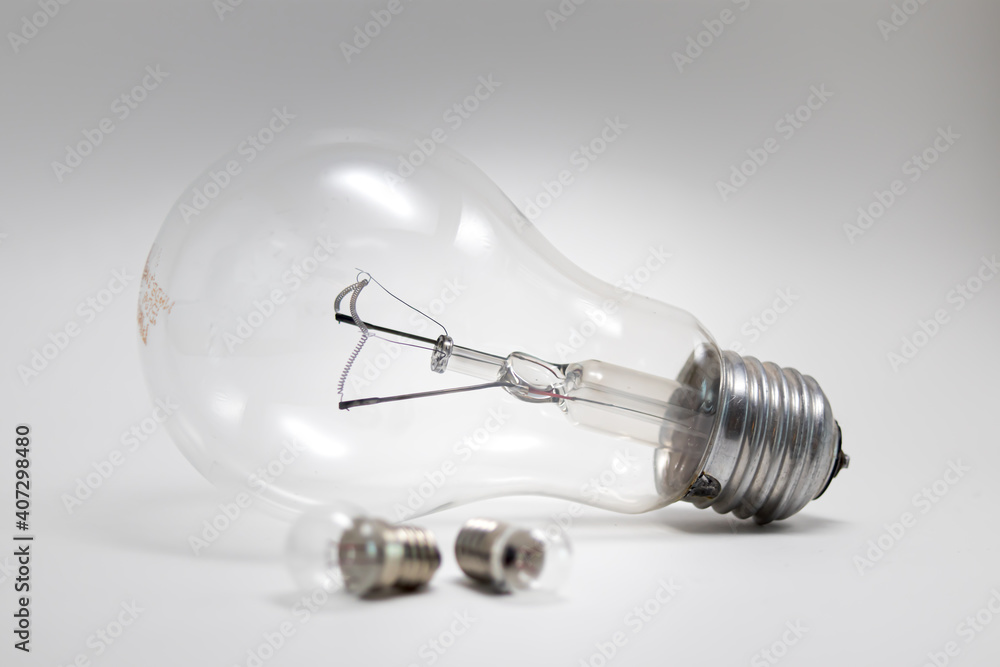 Transparent electric light bulb lying on the table, two small light bulbs in front of the biggest one, black and white photo Transparent electric light bulb lying on the table, two small light bulbs in front of the biggest one, black and white photo