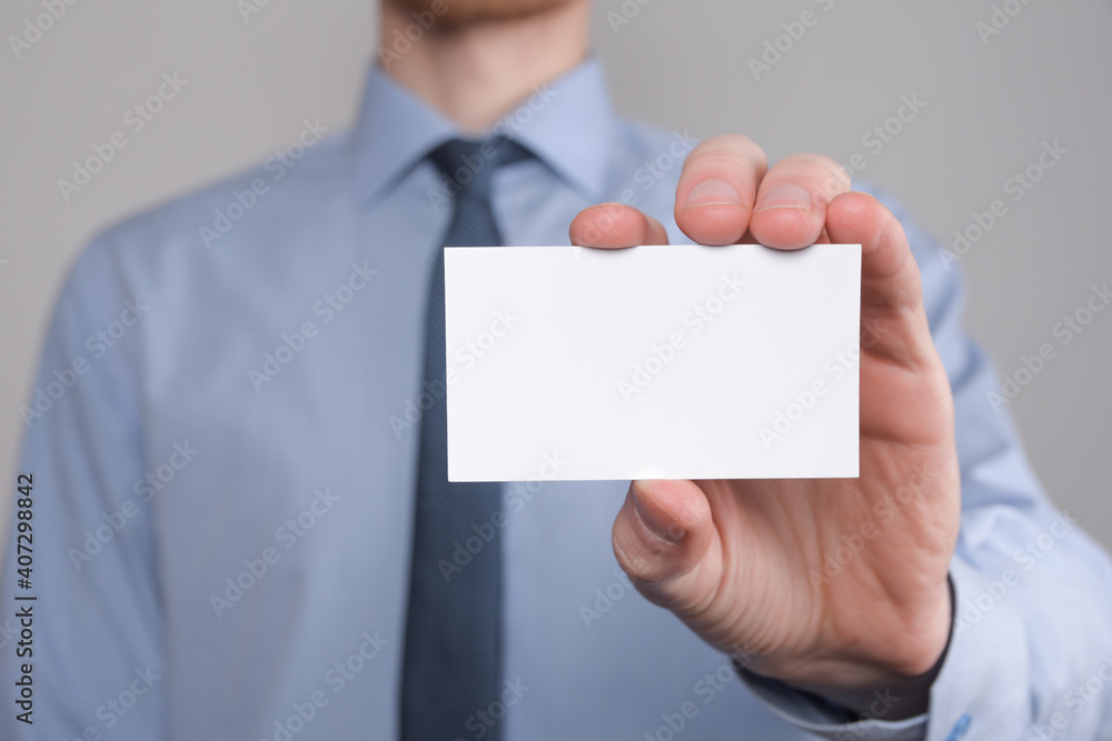 Businessman ,Business Man's hand hold showing business card - close up shot on grey background. Show a blank piece of paper. Paper visit card Businessman ,Business Man's hand hold showing business card - close up shot on grey background. Show a blank piece of paper. Paper visit card