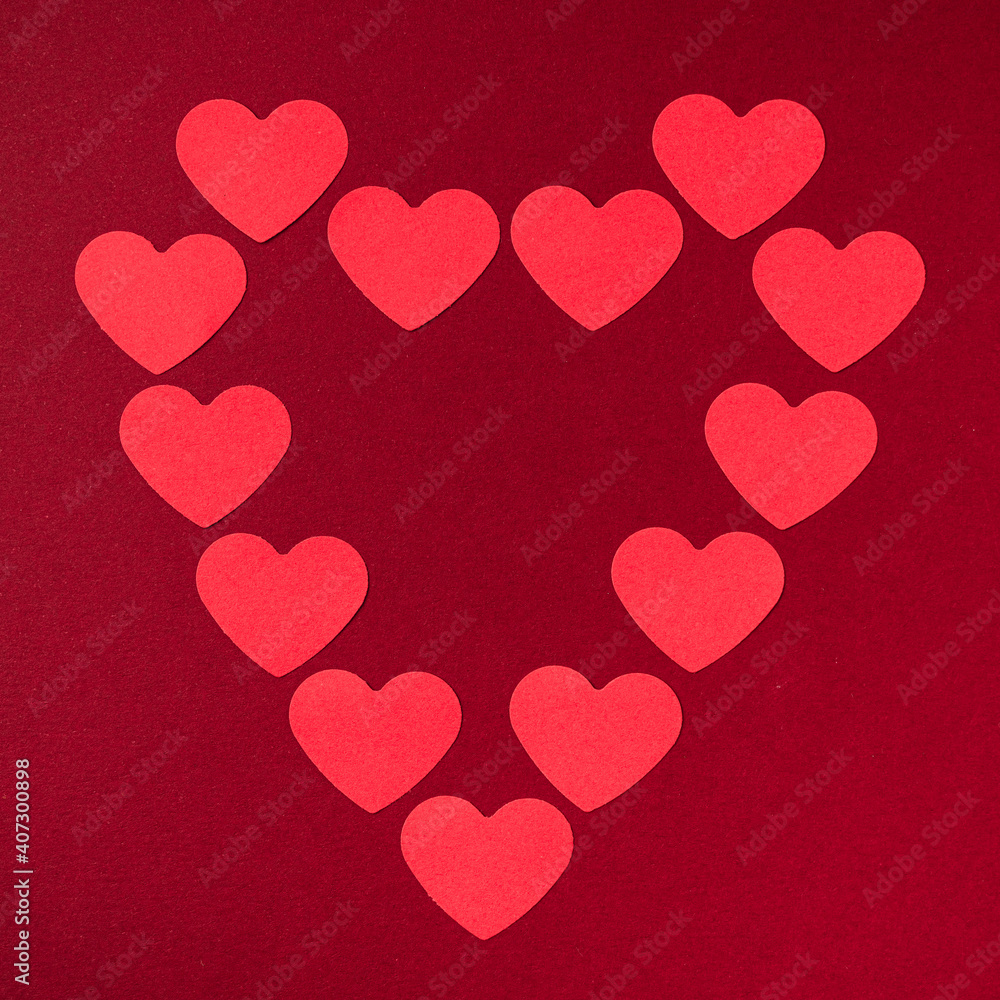 Big symmetrical heart shape made from small, heart shaped red papers on a dark red background. Valentines Day background.