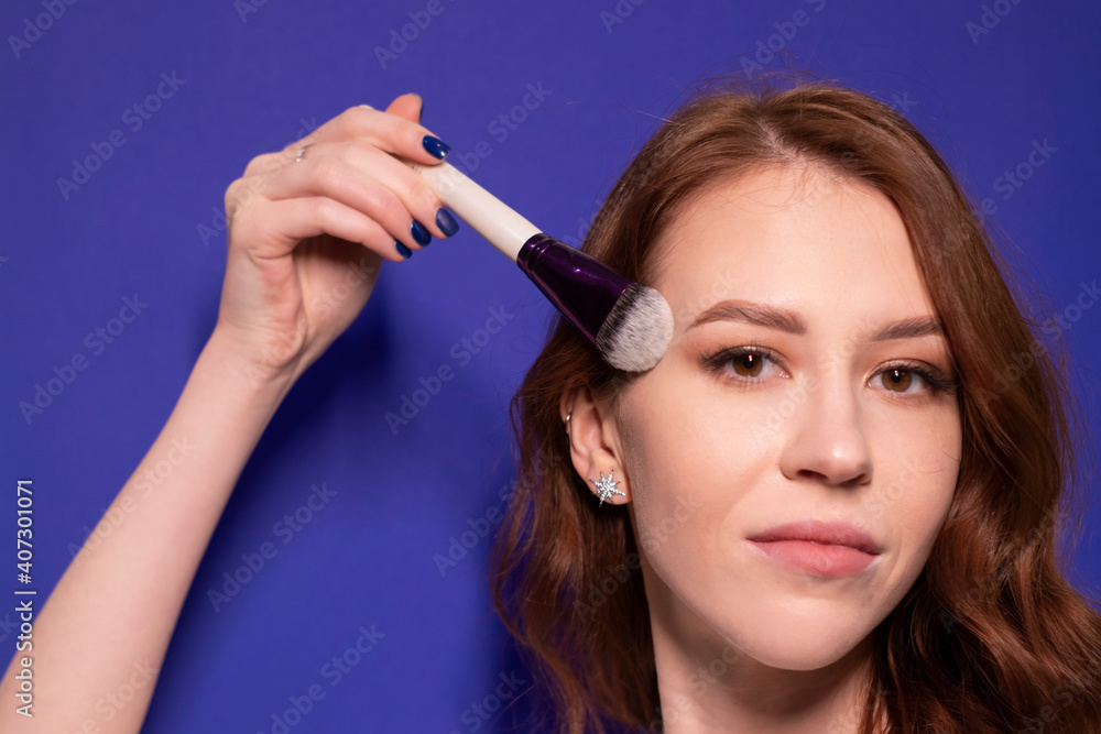 charming brunette woman in white t-shirt with makeup brushes isolated on colorful blue background. professional makeup artist