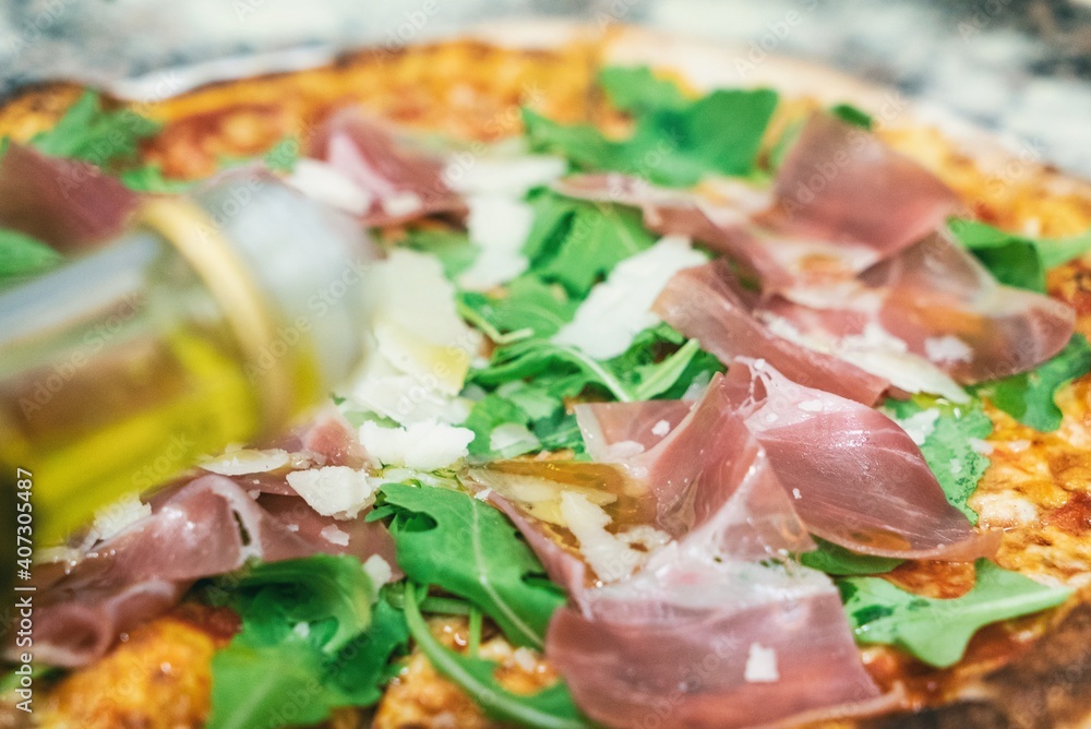 Pizza from the oven. Oven-baked pizza with Italian ham and arugula close up Pizza from the oven. Oven-baked pizza with Italian ham and arugula close up