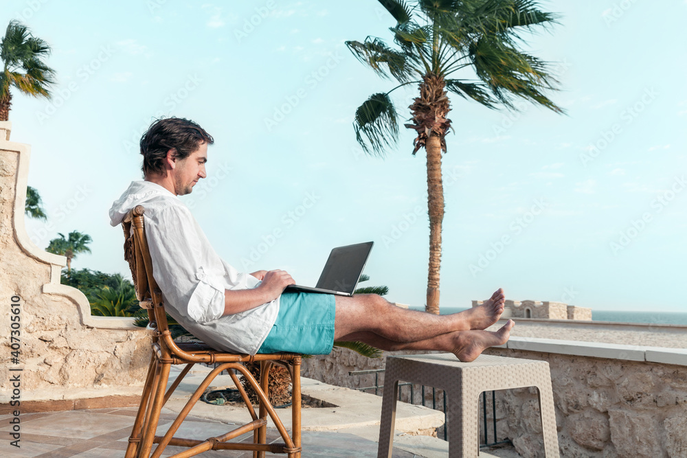 freelancer with a laptop in his hands works on vacation