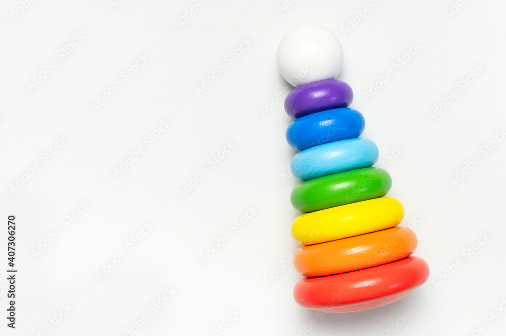 Multi-colored wooden children's toy pyramid on white background. Eco friendly toy, plastic free. Toy for babies and toddlers. Natural wood toys. Colors of rainbow. Flat lay top view copy space Multi-colored wooden children's toy pyramid on white background. Eco friendly toy, plastic free. Toy for babies and toddlers. Natural wood toys. Colors of rainbow. Flat lay top view copy space