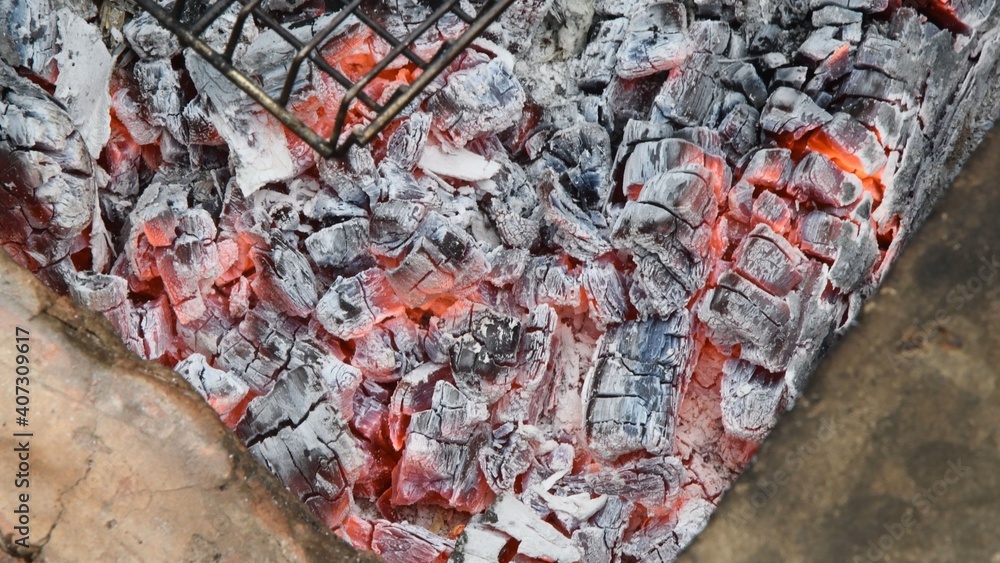 Natural wooden coals burning for barbecue, smoldering and glowing in grill, for preparing grilled food. Blurred background of smolder charcoals. Hot embers texture