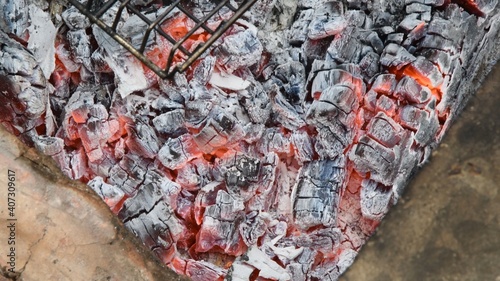 Natural wooden coals burning for barbecue, smoldering and glowing in grill, for preparing grilled food. Blurred background of smolder charcoals. Hot embers texture