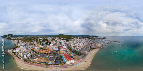 Aerial drone 360 Degree panoramic sphere aerial photo of the beautiful beach front of Ibiza in Spain showing the Spanish beach and harbour with boats in the ocean from above