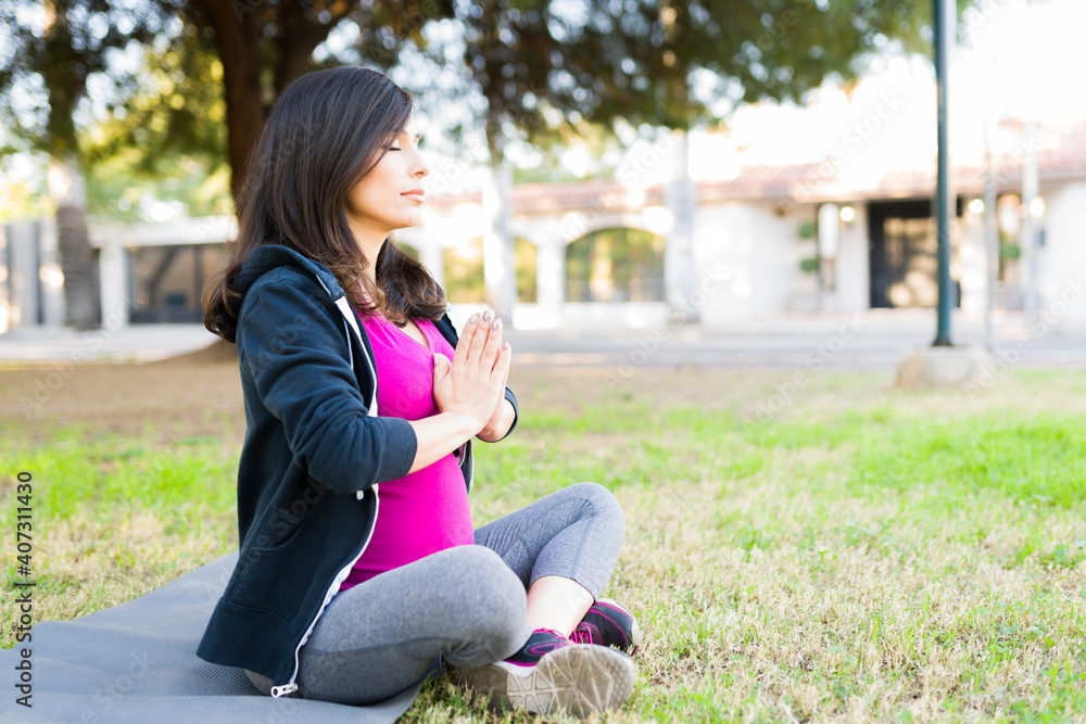 Pregnant woman meditating in a prayer pose Pregnant woman meditating in a prayer pose