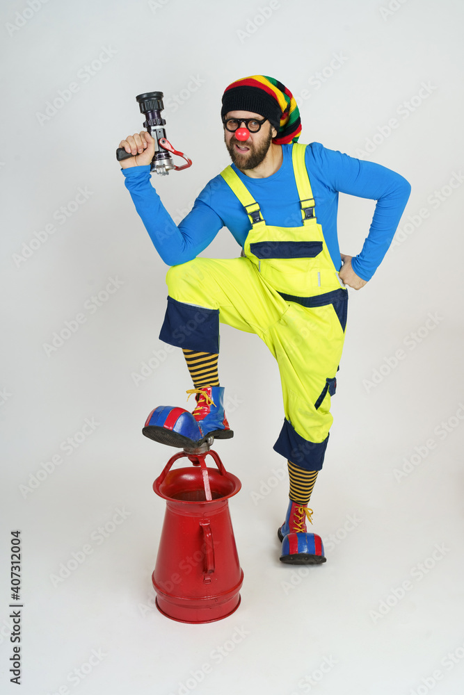 The clown firefighter holds a fire barrel in his hands, extinguishes the fire. The clown firefighter holds a fire barrel in his hands, extinguishes the fire.