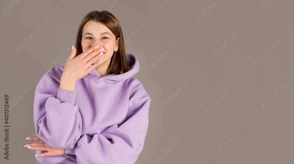 Surprised woman covering her mouth by the hands isolated on gray background Surprised woman covering her mouth by the hands isolated on gray background