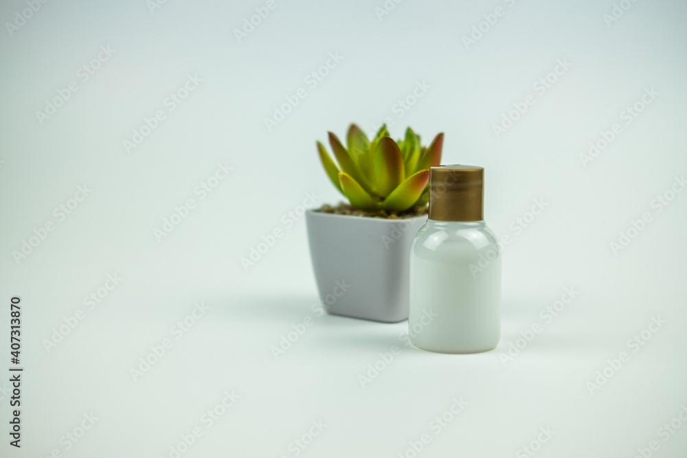 A photo of a little bottle of shower gel in back a little plastic jar with a plant A photo of a little bottle of shower gel in back a little plastic jar with a plant