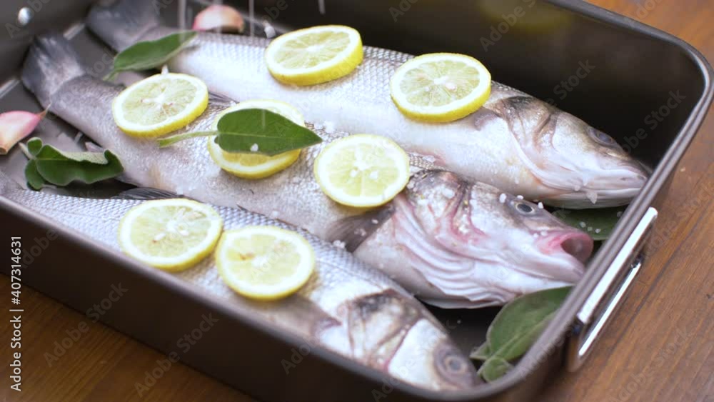 fresh sea bass pready for cooking in the pan with lemon slices and sage fresh sea bass pready for cooking in the pan with lemon slices and sage