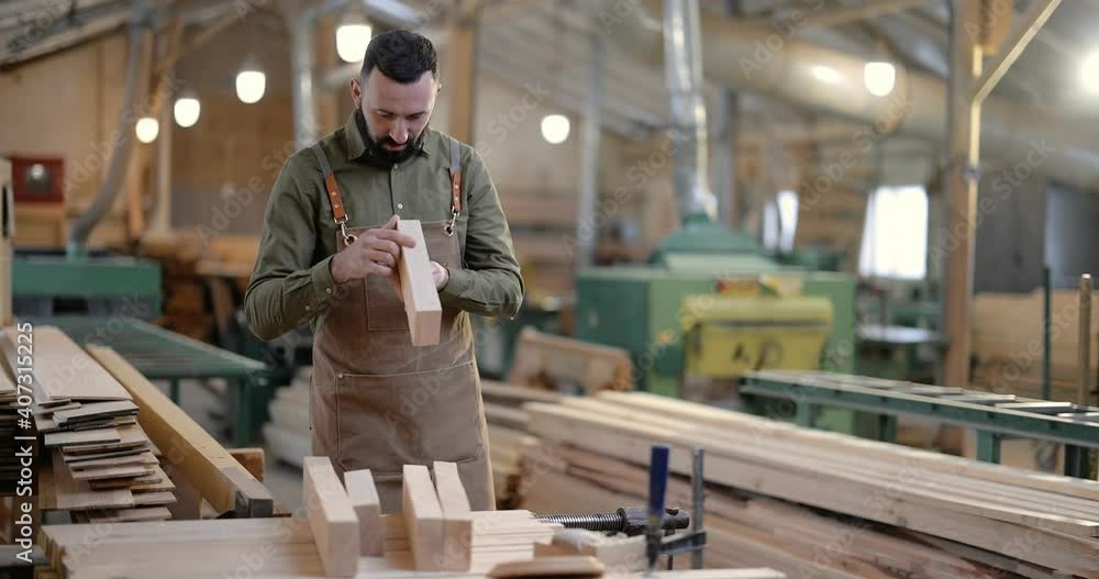 Carpenter looking on planks for some woodwork at the manufacturing. Handsome man working with wood at the joinery Carpenter looking on planks for some woodwork at the manufacturing. Handsome man working with wood at the joinery