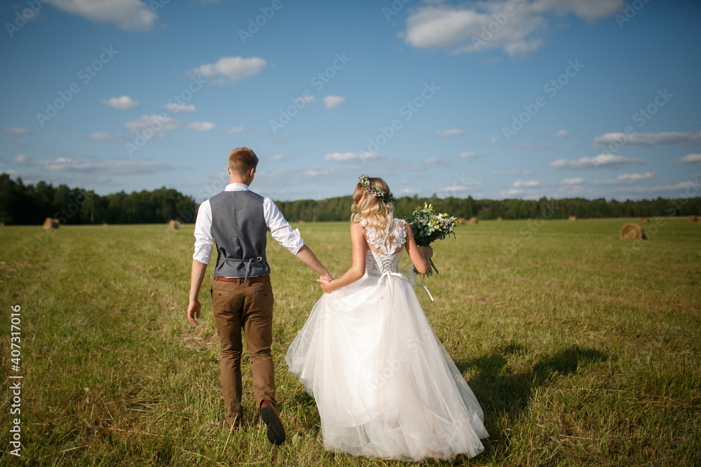 Bride and groom in the field, back view. Wedding couple in nature.