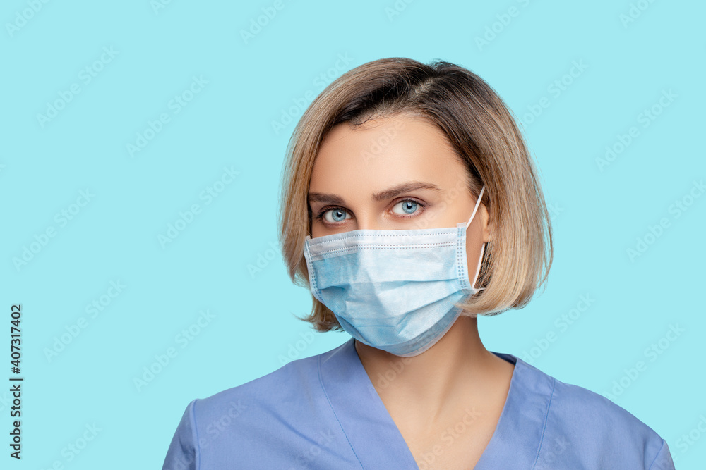 Portrait of a young Woman Doctor wears a protective Mask on a blue background. 