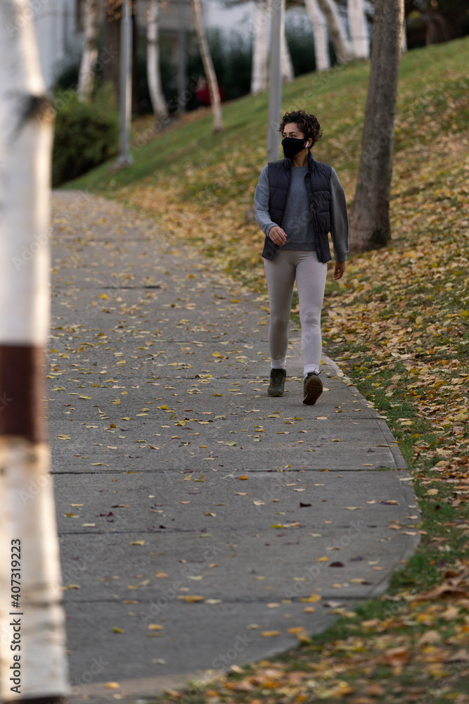 Fototapeta premium woman is doing sports with virus mask in pandemic days in the park