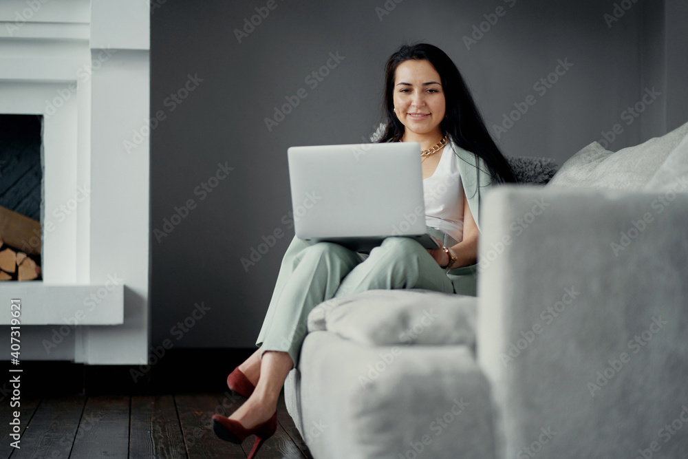 online training for working on a laptop computer on a new project in a stylish office. A young woman of Caucasian appearance is sitting on the sofa. a favorite work, a comfortable business suit online training for working on a laptop computer on a new project in a stylish office. A young woman of Caucasian appearance is sitting on the sofa. a favorite work, a comfortable business suit