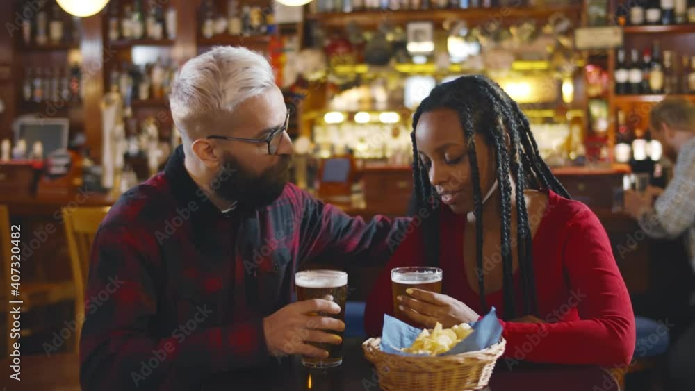 Diverse couple hugging having glass of beer in bar Diverse couple hugging having glass of beer in bar