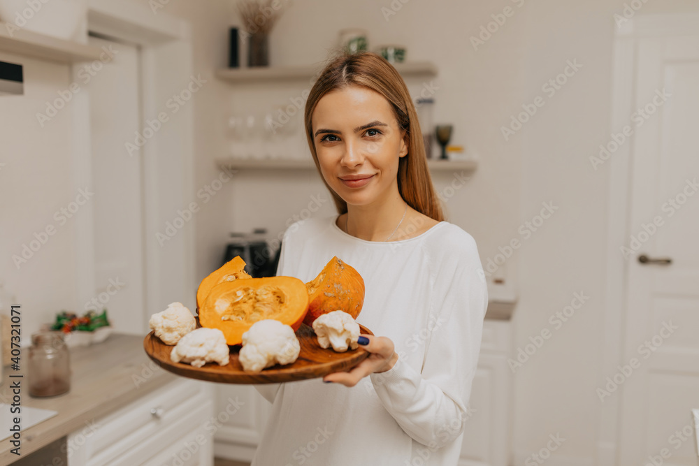 Image of young pretty lady standing in kitchen and cooking vegetables Image of young pretty lady standing in kitchen and cooking vegetables