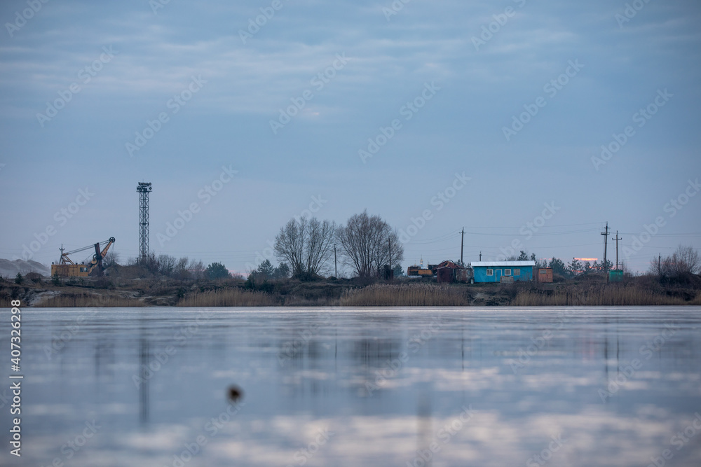 Sand mining equipment is reflected in the ice on the lake