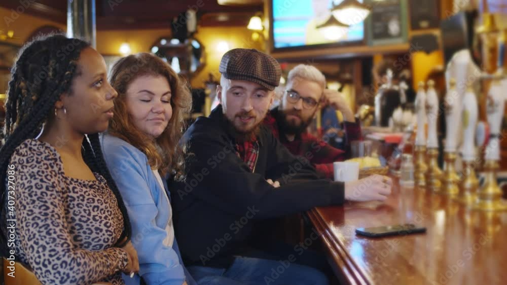 Cheerful diverse friends having fun and drinking draft beer at bar counter in pub. Cheerful diverse friends having fun and drinking draft beer at bar counter in pub.