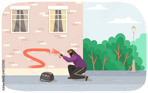 Vandal damaging city building. Bully in hood and balaclava painting graffiti on a brick wall of a residential building. Street gangsters and vandalism concept. A man bandit destroy city property