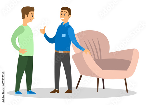 A man smiling shopper in furniture shop, shopping for house, chooses a comfortable chair. Professional department store seller advises the client, helps him make a choice. Two men near the armchair
