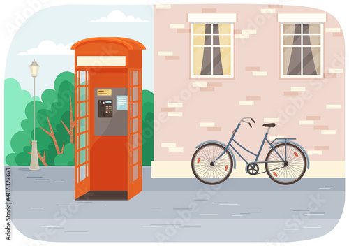 Empty London red classic telephone booth with an open door on the street with a bicycle at the building. City summer landscape with public telephone and brick wall with windows, Empty urban street