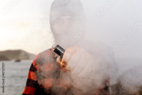 Clenched fist holding an electronic cigarette wrapped in steam. person quitting smoking. boy vaping.