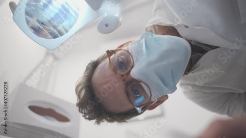 POV dentist doctor examine patient mouth with an explorer and dental mirror. White male orthodontist looking down and examining patient with curiosity. Modern dentistry concept.