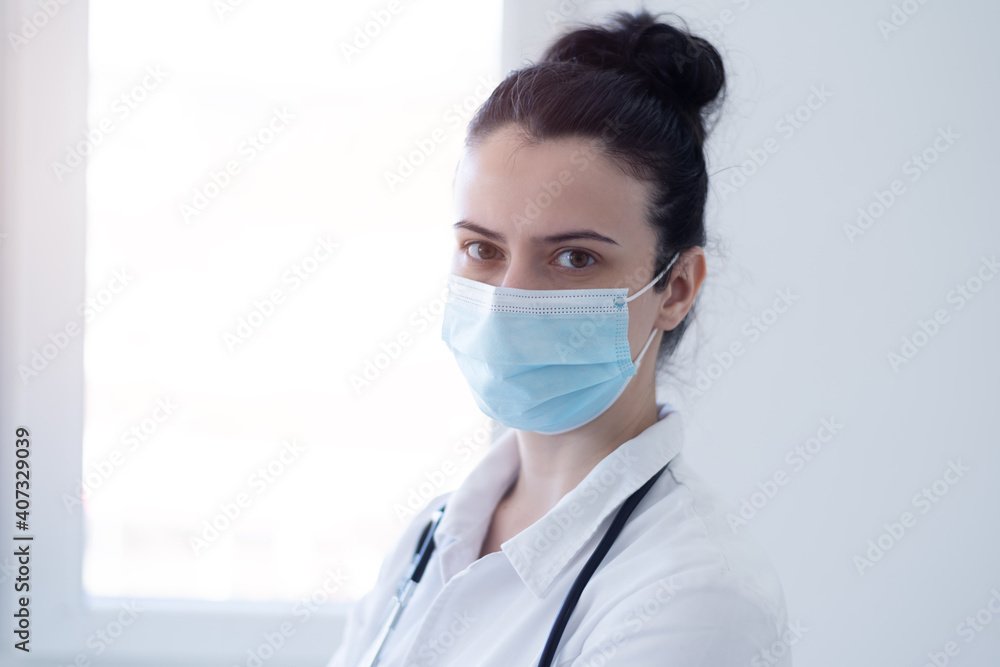 COVID-19 concept Female doctor wearing protective mask and looking into camera during pandemic. COVID-19 concept Female doctor wearing protective mask and looking into camera during pandemic.