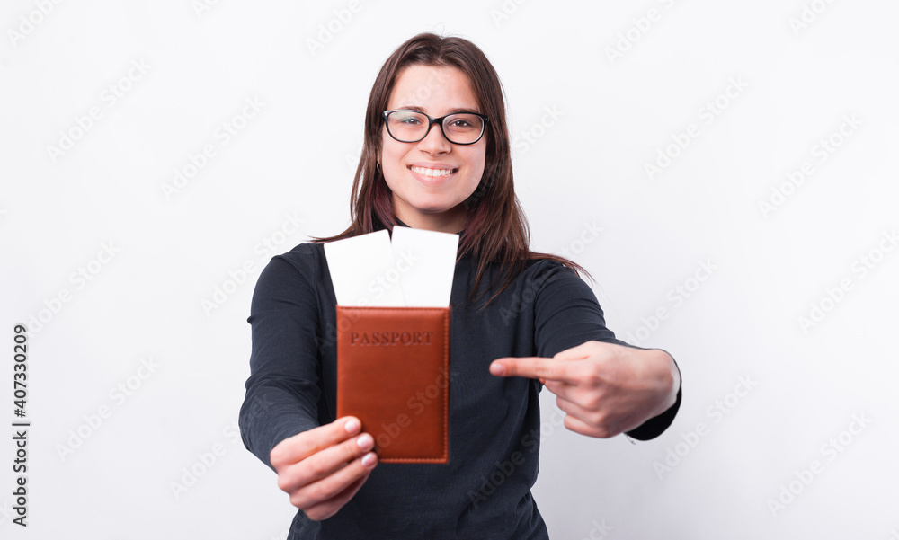 Happy girl pointing at passport and tickets over white background. Happy girl pointing at passport and tickets over white background.