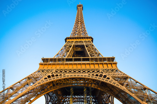 Detail bottom view of Eiffel Tower on the blue sky background in sunset light