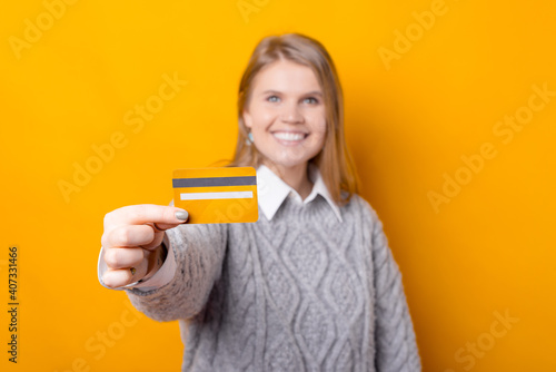 Selective focus on credit card, smiling young woman showing her card.